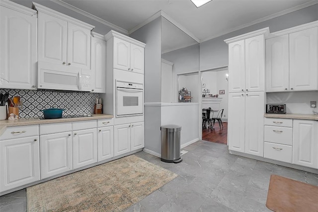 kitchen featuring crown molding, white appliances, tasteful backsplash, and white cabinets