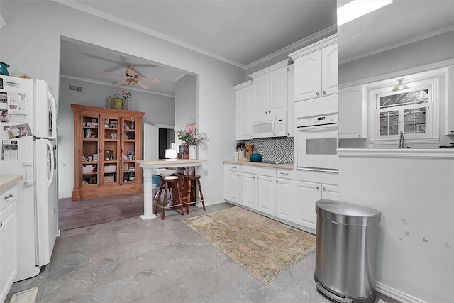 kitchen featuring sink, crown molding, tasteful backsplash, white appliances, and white cabinets