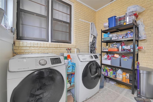 clothes washing area featuring light tile patterned flooring, washer and clothes dryer, ornamental molding, and brick wall