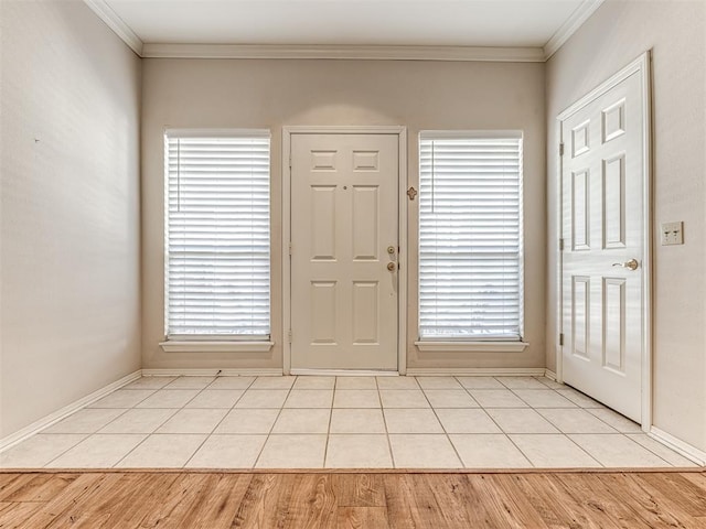 foyer entrance with crown molding, a healthy amount of sunlight, and light tile patterned floors