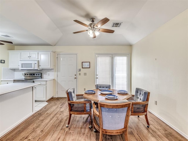 dining space with vaulted ceiling, ceiling fan, and light wood-type flooring