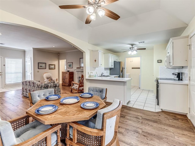 dining space with ceiling fan, ornamental molding, sink, and light wood-type flooring