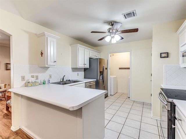 kitchen with tasteful backsplash, sink, white cabinets, and appliances with stainless steel finishes