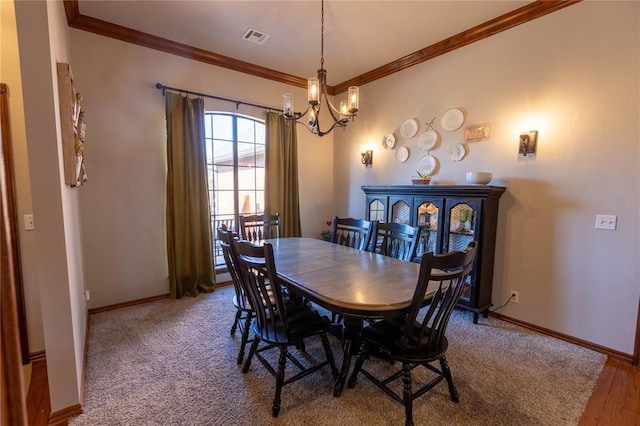 dining room with ornamental molding, a chandelier, and carpet