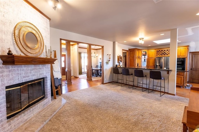 carpeted living room with ornate columns and a tile fireplace