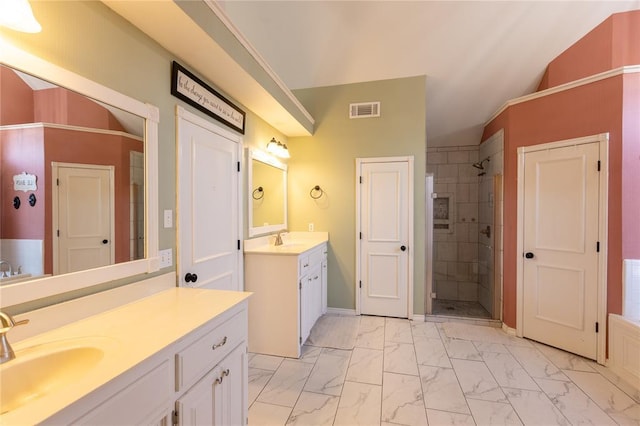 bathroom featuring vanity, vaulted ceiling, and tiled shower