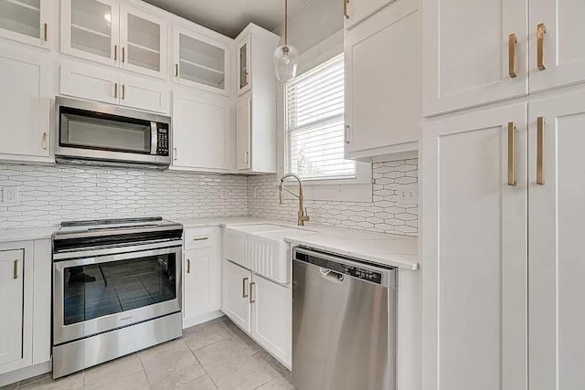 kitchen featuring white cabinetry, appliances with stainless steel finishes, light tile patterned floors, and pendant lighting