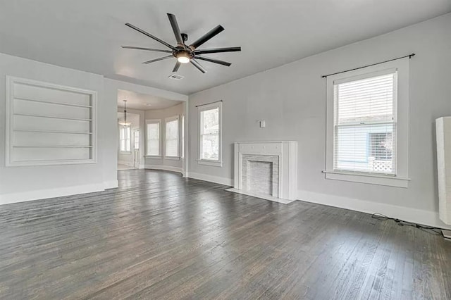 unfurnished living room featuring built in shelves, dark hardwood / wood-style floors, and ceiling fan