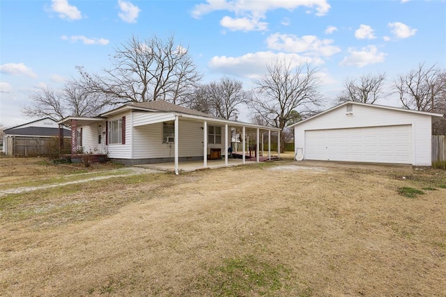 view of front of home featuring covered porch, a front yard, an outdoor structure, and a garage