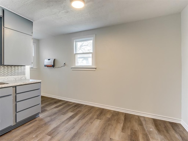 kitchen featuring gray cabinets, a textured ceiling, and light wood-type flooring