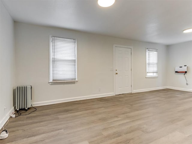 empty room featuring radiator heating unit and light hardwood / wood-style flooring