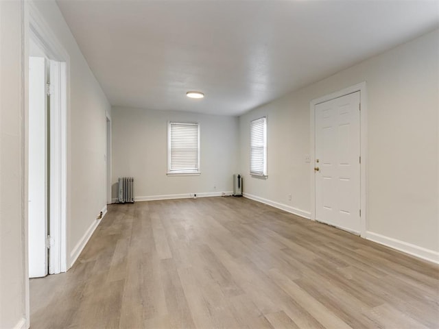 empty room with radiator heating unit and light hardwood / wood-style floors