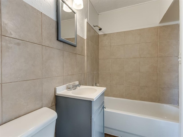 full bathroom with tiled shower / bath, vanity, toilet, and tile walls