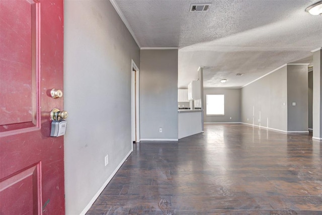 interior space with dark wood-type flooring, a textured ceiling, and ornamental molding