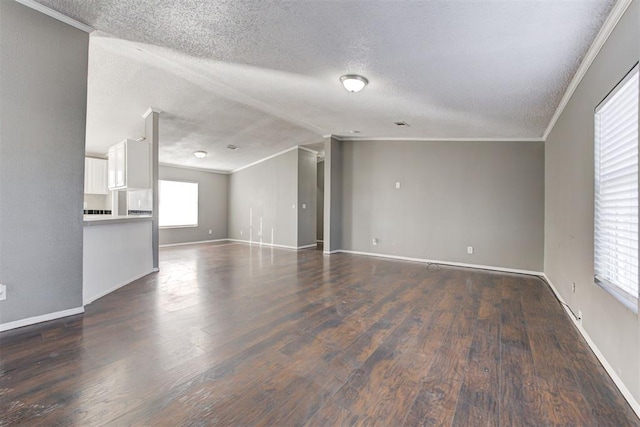 empty room with dark wood-type flooring, a textured ceiling, vaulted ceiling, and ornamental molding