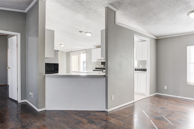 kitchen with crown molding, white cabinetry, range, and dark hardwood / wood-style flooring