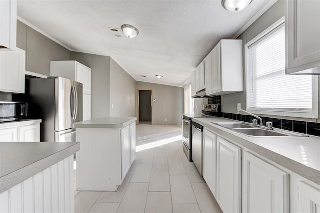 kitchen featuring vaulted ceiling, appliances with stainless steel finishes, sink, white cabinets, and a textured ceiling