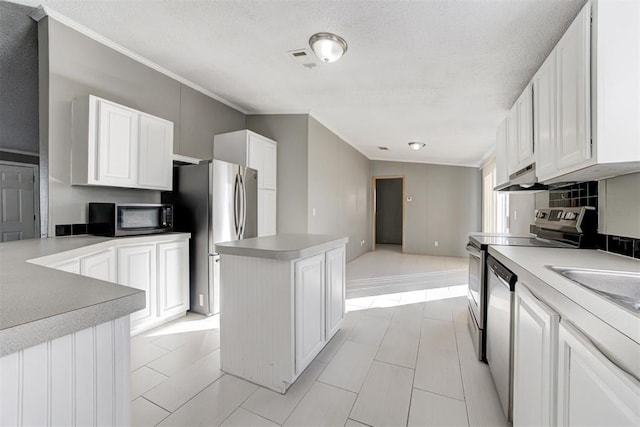 kitchen with a center island, crown molding, white cabinetry, light tile patterned floors, and stainless steel appliances