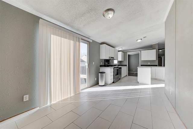 kitchen featuring white cabinets, light tile patterned floors, and stainless steel range with electric cooktop