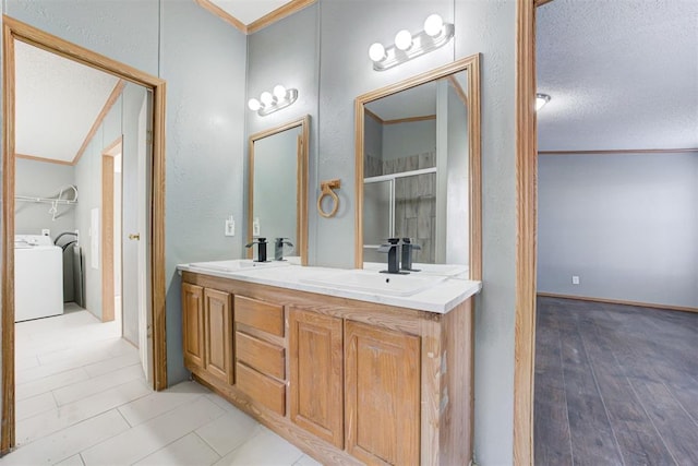 bathroom featuring a textured ceiling, lofted ceiling, washer / clothes dryer, vanity, and crown molding