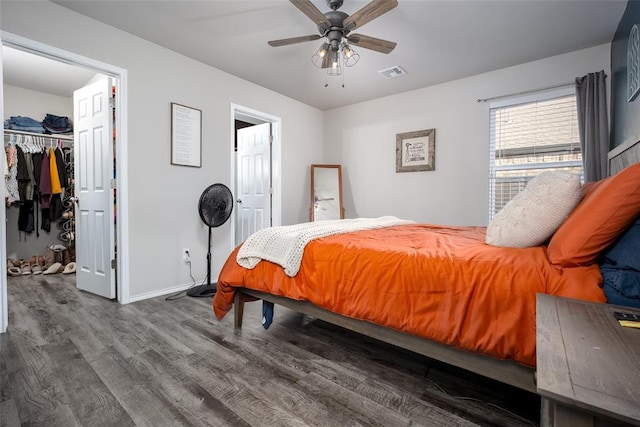 bedroom with hardwood / wood-style flooring, a walk in closet, ceiling fan, and a closet