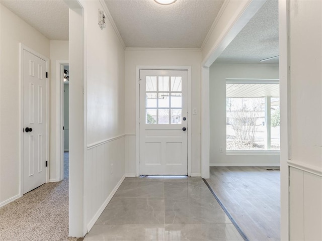 doorway to outside with ornamental molding, a healthy amount of sunlight, and a textured ceiling