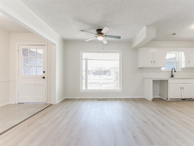 kitchen with white cabinetry, a textured ceiling, light hardwood / wood-style floors, and decorative backsplash