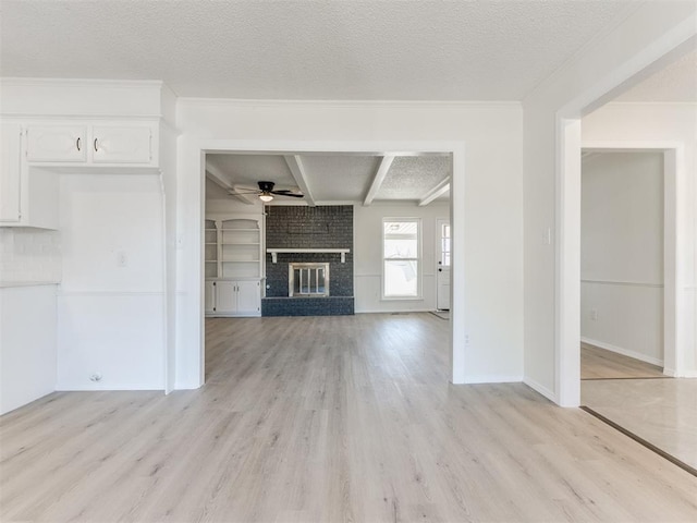 unfurnished living room with beamed ceiling, a fireplace, a textured ceiling, and light hardwood / wood-style floors