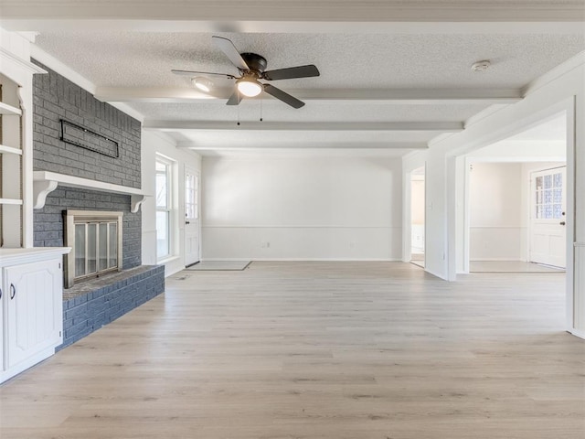 unfurnished living room featuring beam ceiling, a fireplace, and a textured ceiling