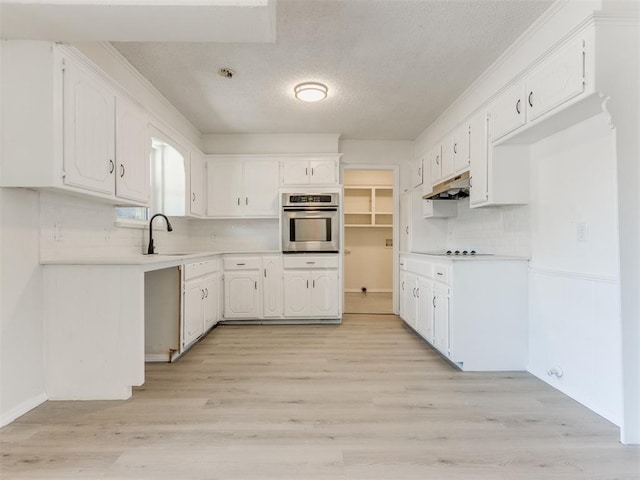 kitchen featuring white cabinetry, oven, backsplash, and light hardwood / wood-style flooring