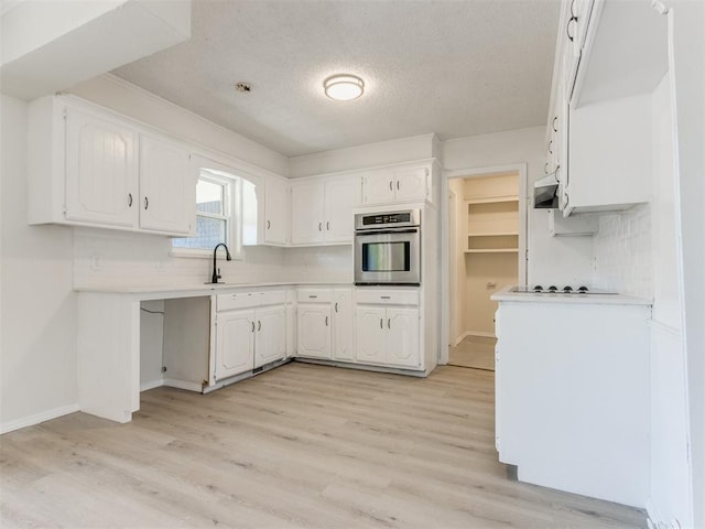 kitchen featuring white cabinetry, stainless steel oven, black electric cooktop, and light hardwood / wood-style flooring