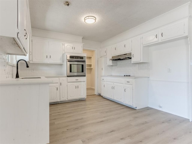 kitchen featuring white cabinets, light hardwood / wood-style floors, sink, and stainless steel oven