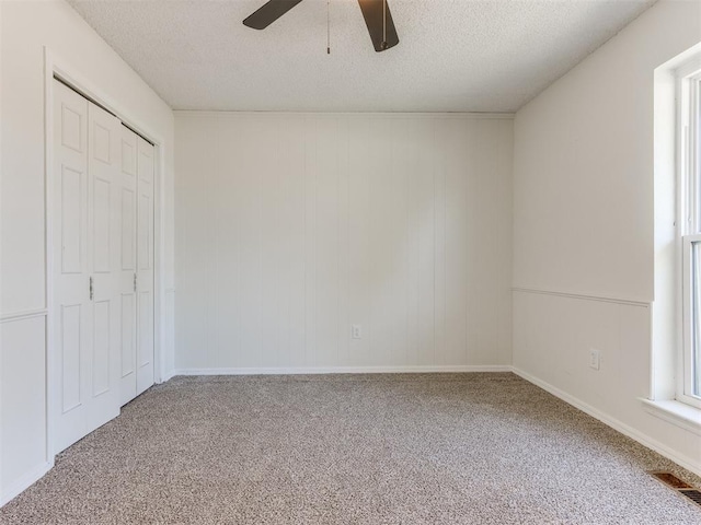 unfurnished bedroom with ceiling fan, carpet flooring, a textured ceiling, and a closet