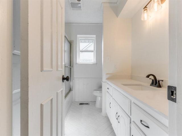 full bathroom with vanity, ornamental molding, combined bath / shower with glass door, and toilet