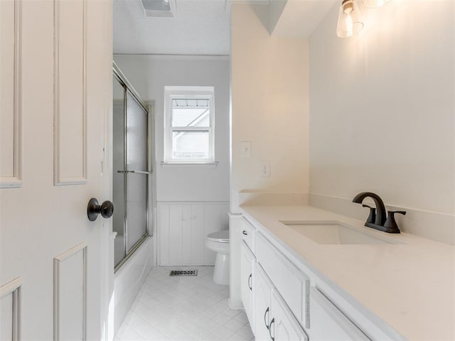 full bathroom with crown molding, shower / bath combination with glass door, tile patterned flooring, vanity, and toilet