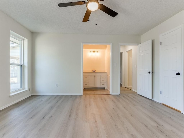 unfurnished bedroom featuring sink, ceiling fan, connected bathroom, a textured ceiling, and light wood-type flooring