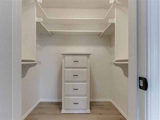 walk in closet with light hardwood / wood-style flooring