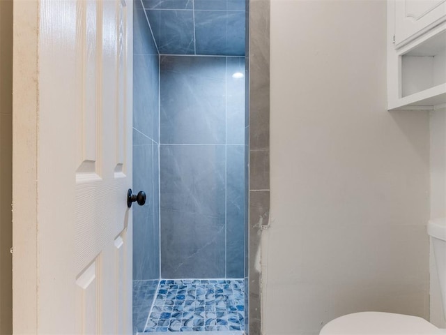 bathroom with a tile shower and toilet