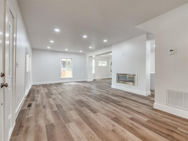 unfurnished living room featuring heating unit and light hardwood / wood-style flooring