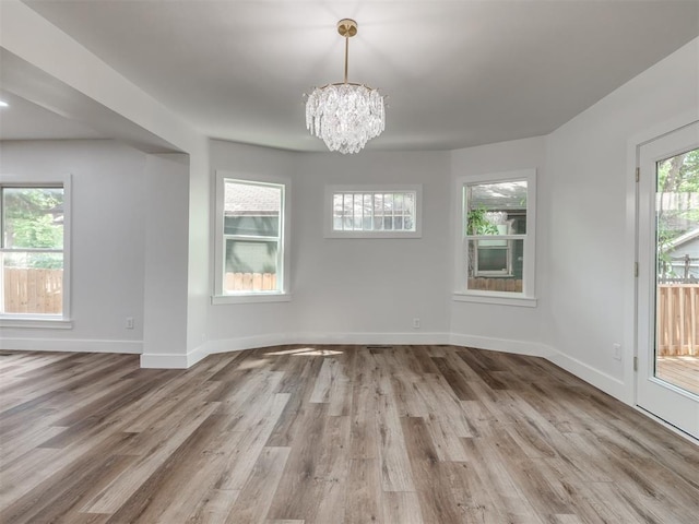 unfurnished dining area featuring wood-type flooring and a notable chandelier