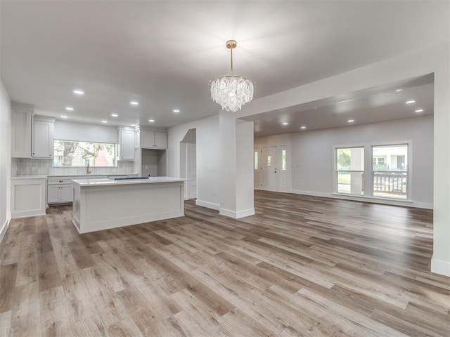 unfurnished living room featuring a healthy amount of sunlight, light hardwood / wood-style floors, and a notable chandelier