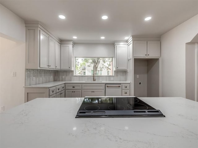 kitchen with light stone counters, sink, black stovetop, and dishwasher