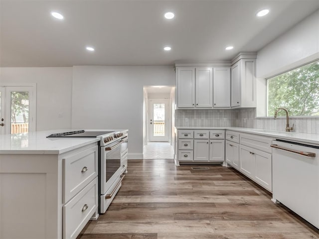 kitchen with tasteful backsplash, sink, white cabinets, plenty of natural light, and white appliances