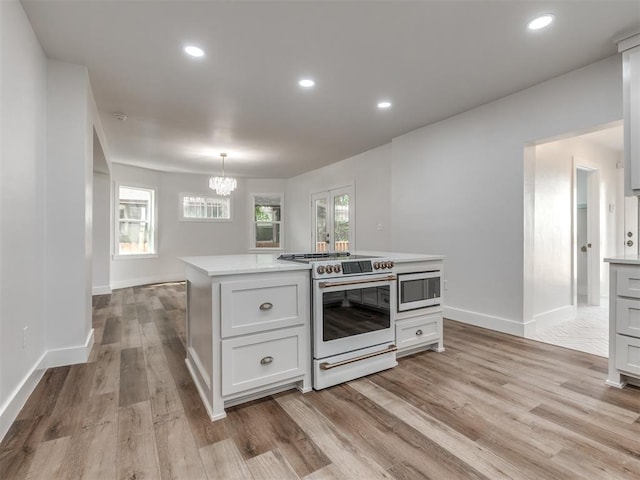 kitchen featuring white electric range, white cabinetry, decorative light fixtures, light hardwood / wood-style flooring, and a notable chandelier