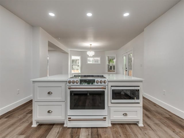 kitchen with white cabinetry, white appliances, hardwood / wood-style floors, and hanging light fixtures