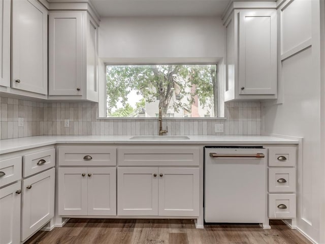 kitchen with sink, hardwood / wood-style flooring, dishwasher, white cabinetry, and tasteful backsplash