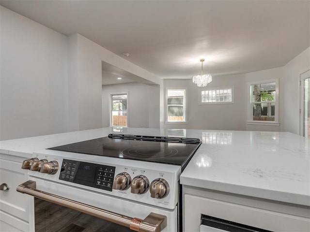 kitchen featuring light stone counters, white cabinetry, an inviting chandelier, hanging light fixtures, and electric range