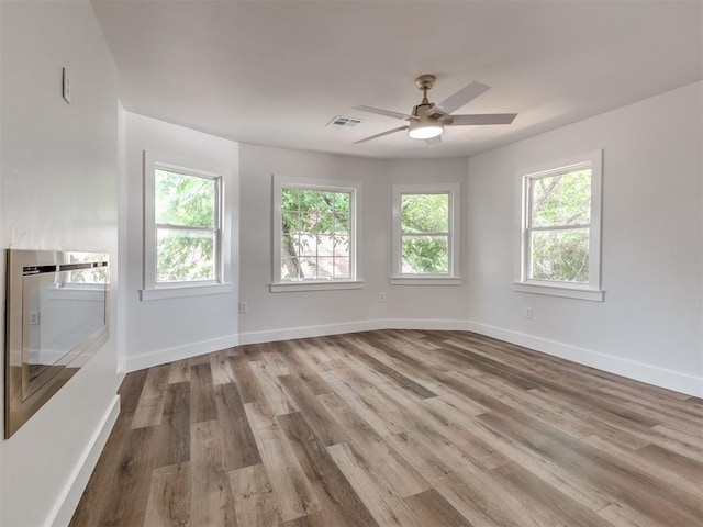 spare room with ceiling fan, plenty of natural light, and light wood-type flooring