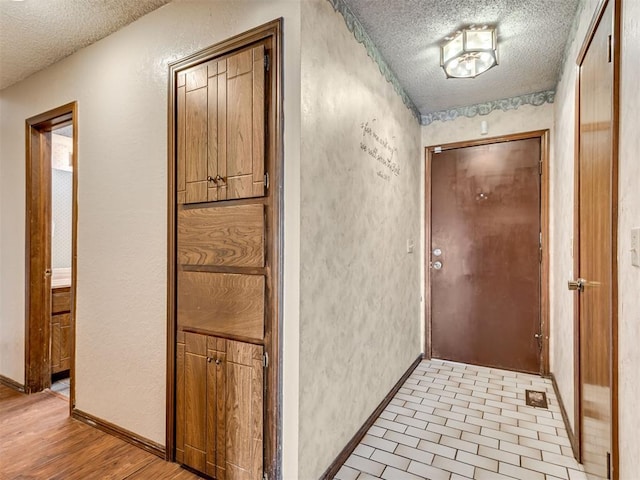 corridor featuring light hardwood / wood-style flooring and a textured ceiling