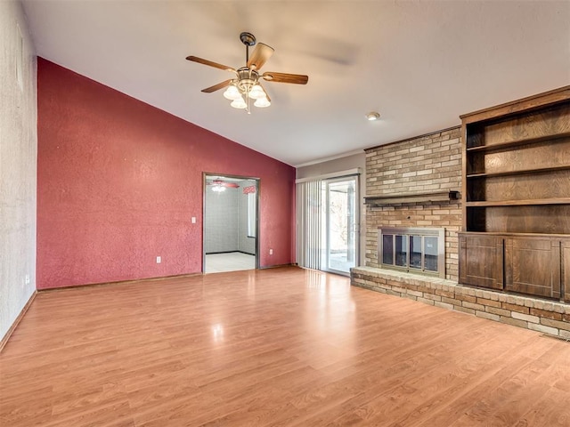 unfurnished living room with a brick fireplace, vaulted ceiling, ceiling fan, and light wood-type flooring